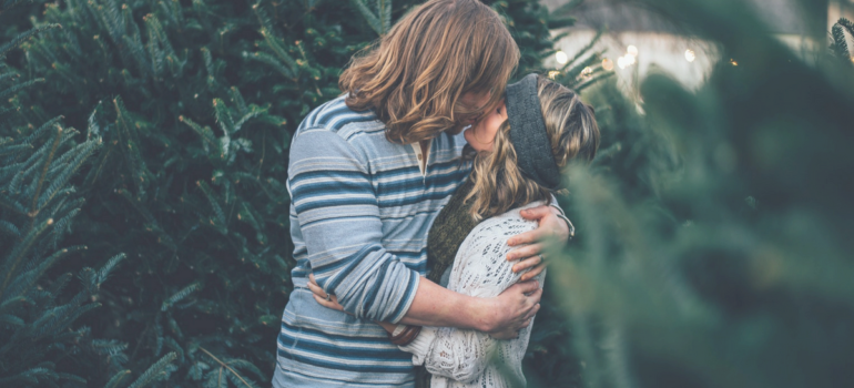 Young Couple Kissing near Evergreen Trees